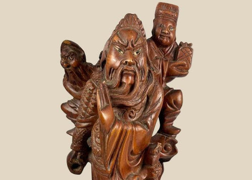 Antique Chinese Qing Dynasty-era wood carving of a warrior immortal figure, intricately detailed with flowing robes, fierce expression, and symbolic weaponry, standing atop a carved base; traditional hand-carved craftsmanship with dark polished patina, reflecting religious and cultural artistry of Qing Dynasty China.