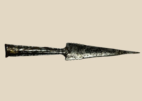 Forged iron spearhead from Europe, Iron Age to Early Medieval period (circa 1st millennium CE), featuring a scalloped-edge blade, socketed base, and historic mixed-metal brazed repair. Natural patina and surface texture reflect centuries of use, craftsmanship, and cultural significance as both a functional weapon and symbol of status.