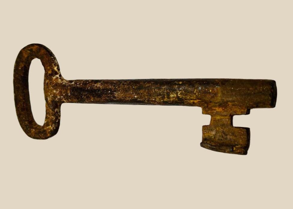 18th-century European forged iron skeleton key with oval bow, wedge-shaped ward, and developed patina, used for warded locks in manors, castles, or estates.