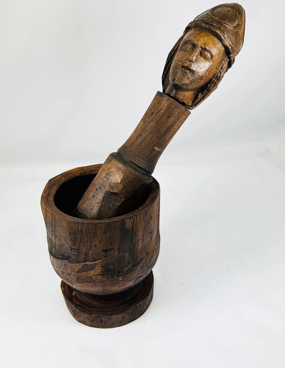 18th–19th Century European wooden mortar and pestle, featuring a finely carved human face on the pestle. The robust mortar and intricately detailed pestle showcase traditional craftsmanship, rich patina, and centuries of use, reflecting both utilitarian function and cultural artistry.