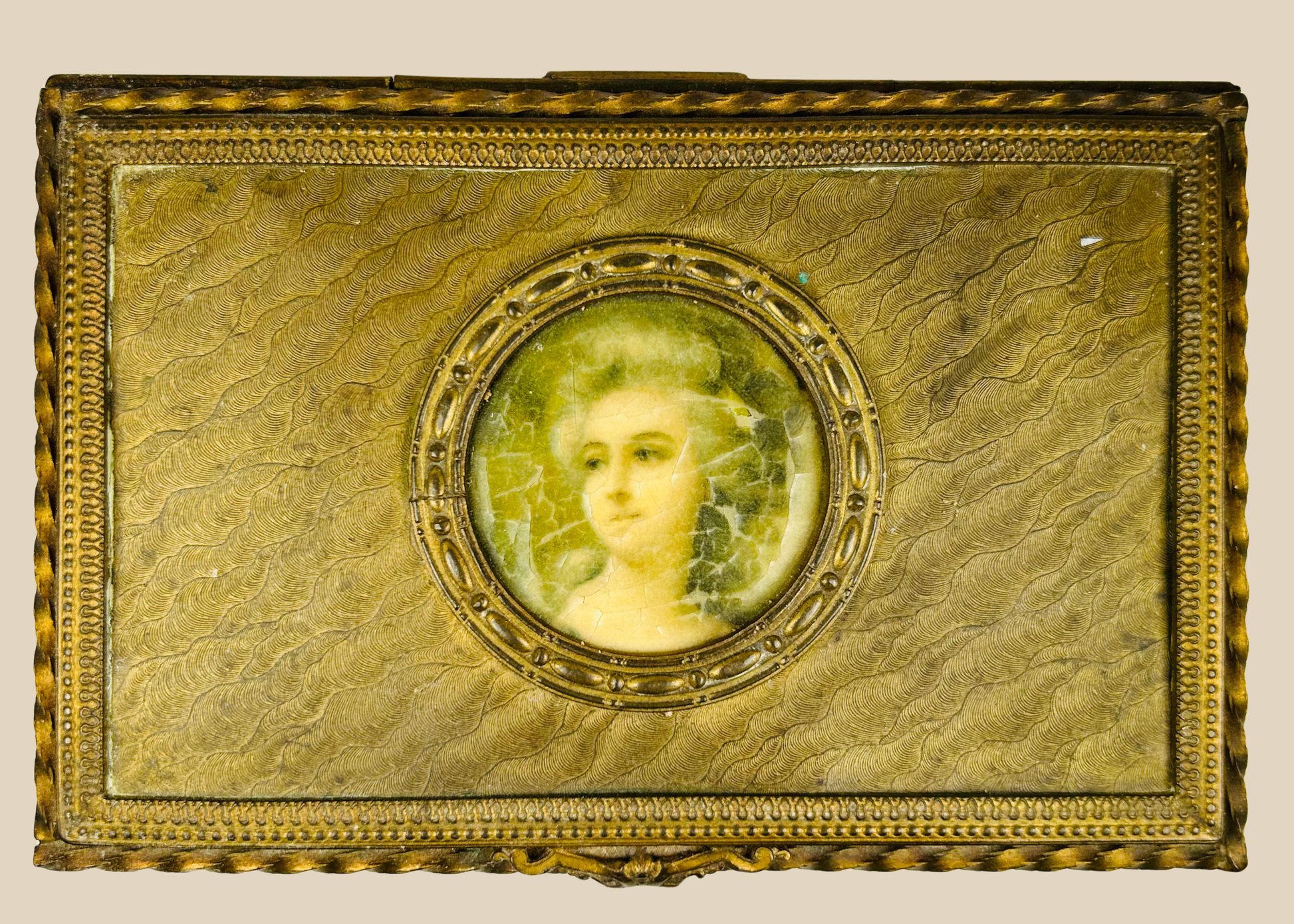Antique gold decorative box featuring a painted portrait miniature of a woman displayed on a beige background.