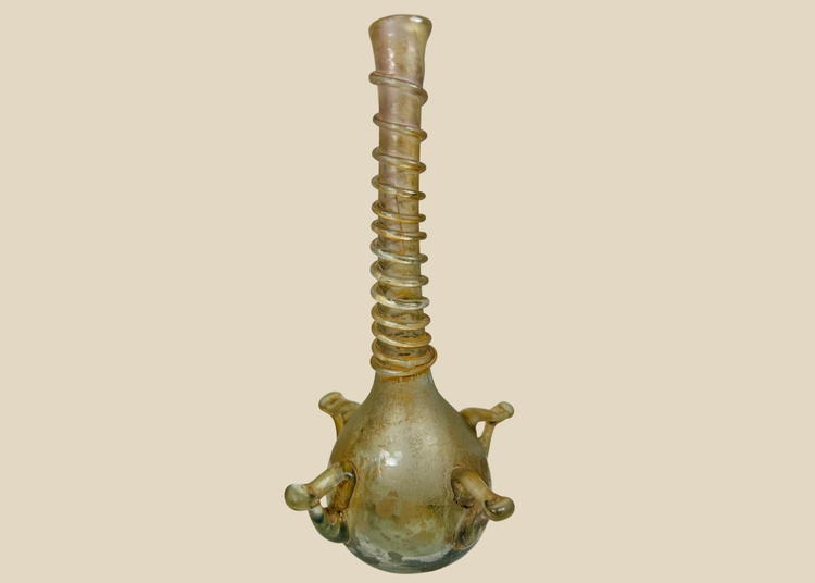 Ancient Islamic glass vessel with ribbed neck and applied handles, translucent green hue, circa 9th–12th century CE.
