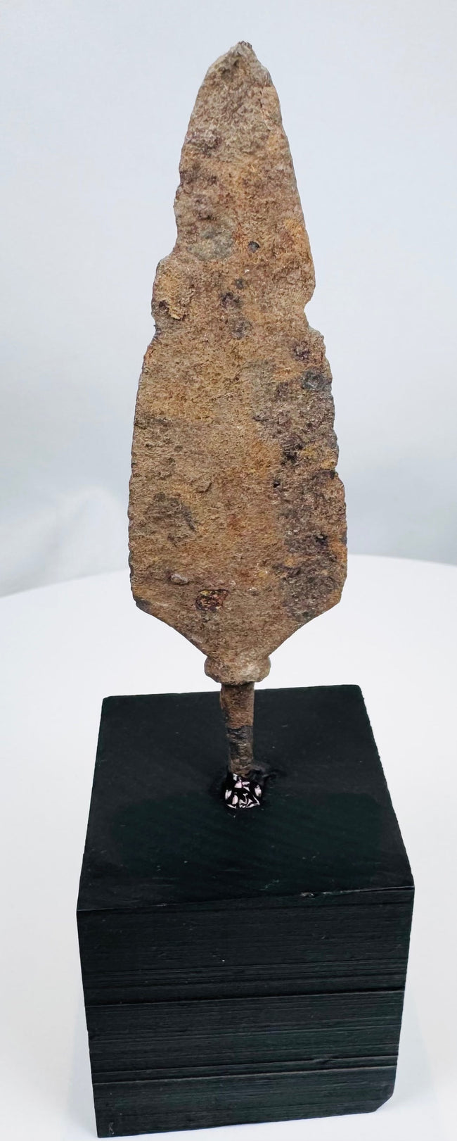 Late Roman or medieval iron projectile head mounted on a black display base