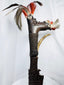 Side view of carved Mandau handle with curved decorative crest and attached feathers