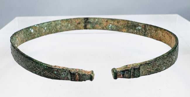Close-up of ancient bronze bracelet showing animal-head terminals and punched ornament