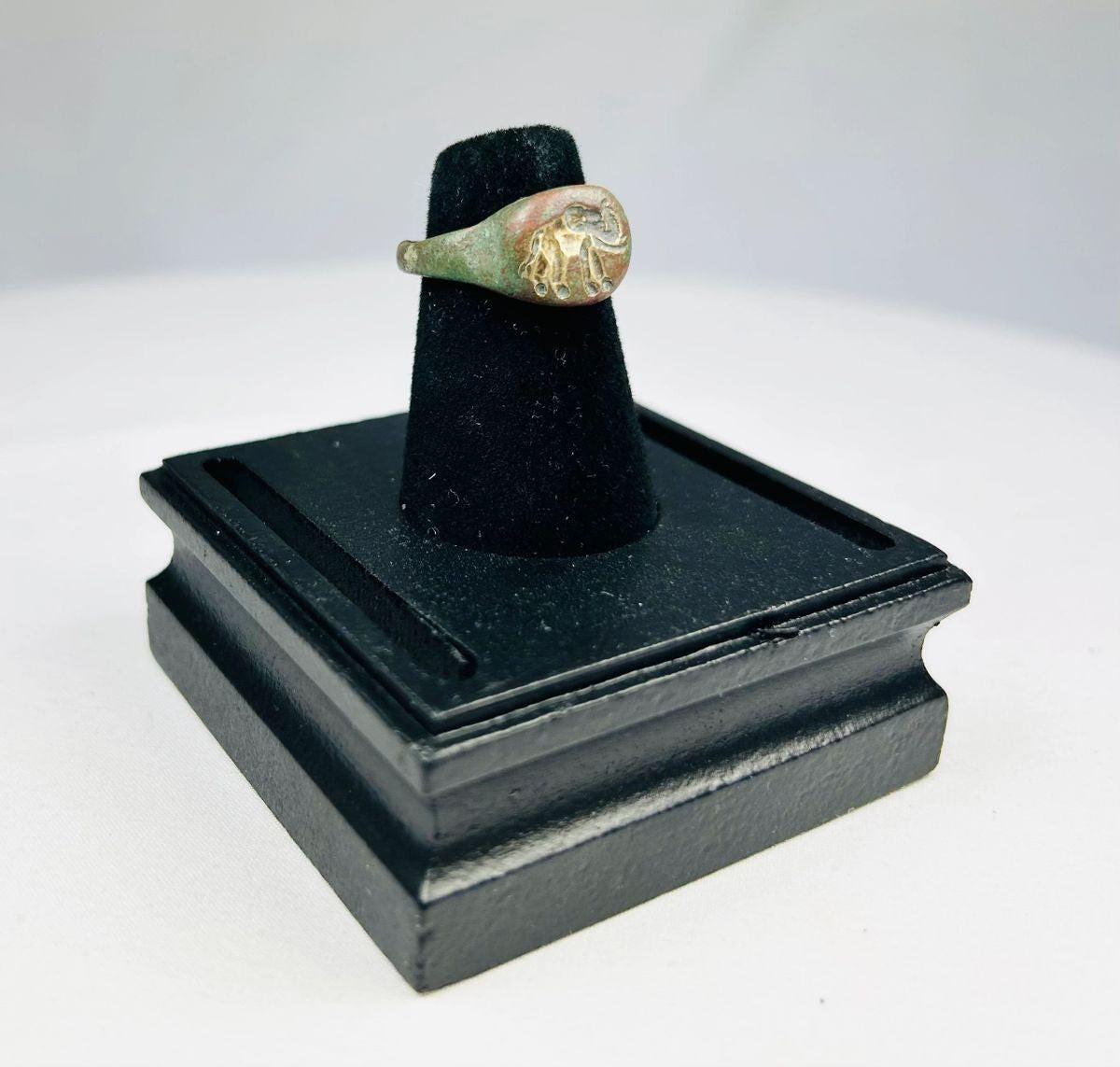 Ancient bronze ring with a finely engraved elephant motif on the bezel, green patina from age, symbolizing wisdom, power, and protection, circa 1st Millennium BCE.