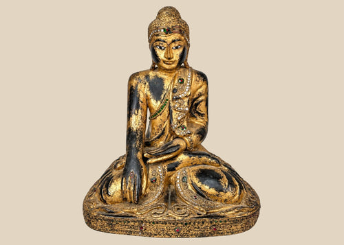 Hand-carved wooden Thai Buddha statue with gilt paint and colorful glass inlays, seated in Bhumisparsha Mudra, symbolizing enlightenment, circa 19th–early 20th century.