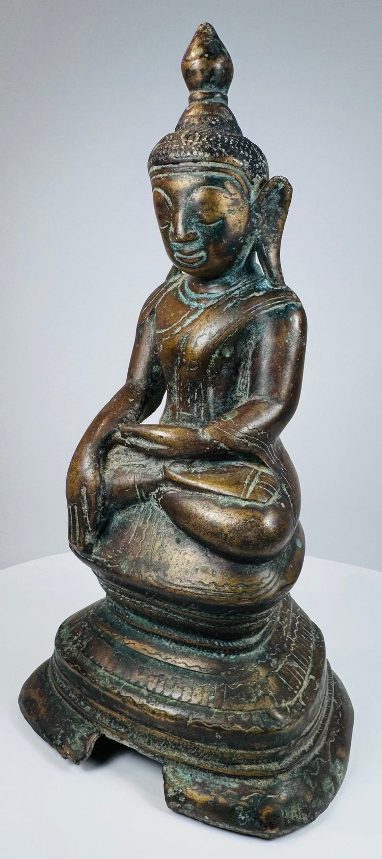 Side profile of the seated Burmese bronze Buddha and lotus-bud finial
