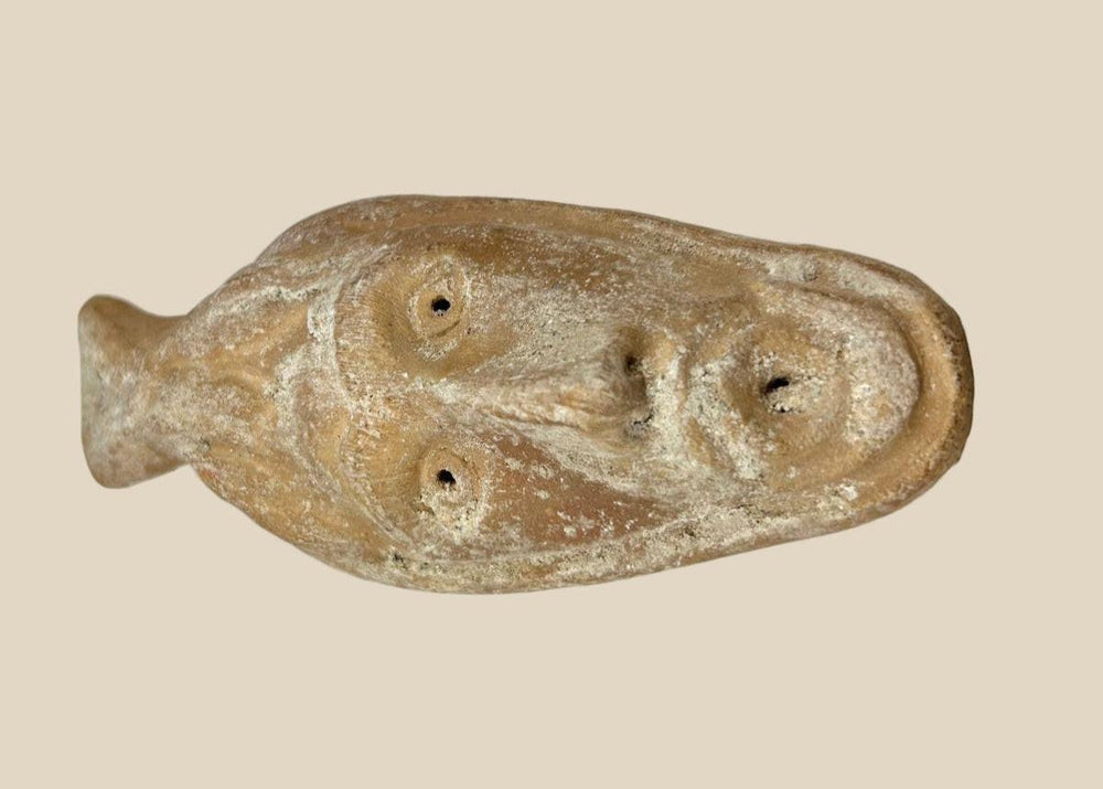 Ancient Byzantine terracotta oil lamp featuring a molded human face with open mouth spout, dating from the 5th to 7th century AD, showing aged surface encrustations.