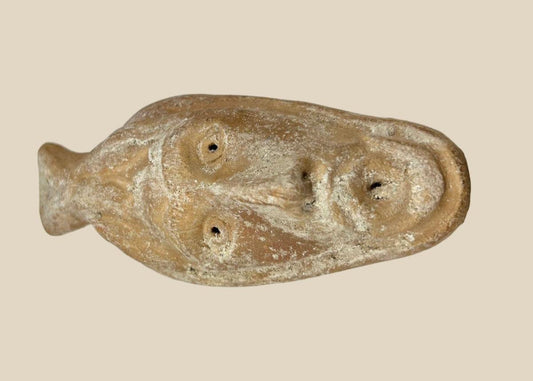 Ancient Byzantine terracotta oil lamp featuring a molded human face with open mouth spout, dating from the 5th to 7th century AD, showing aged surface encrustations.
