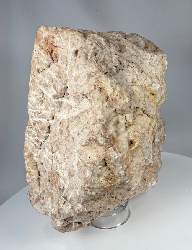 Sculptural medieval stone fragment with relief-carved crucifixion scene and eroded archaeological surface