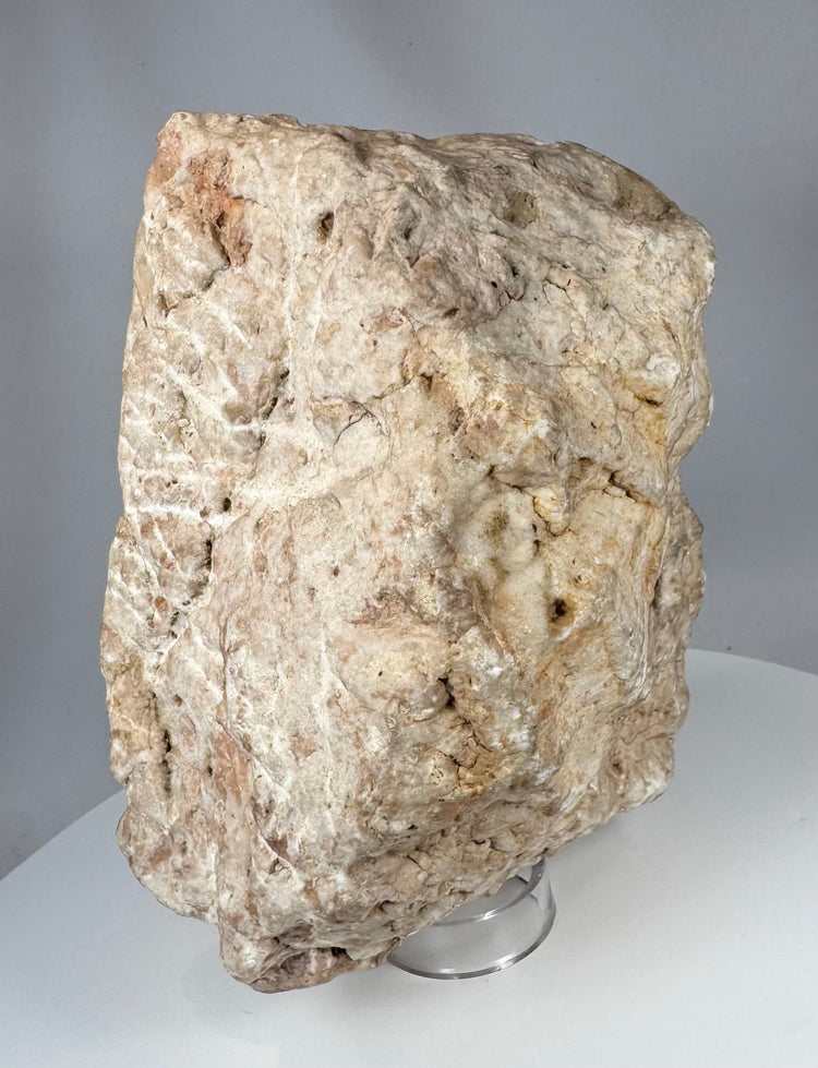 Sculptural medieval stone fragment with relief-carved crucifixion scene and eroded archaeological surface