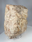 Sculptural medieval stone fragment with relief-carved crucifixion scene and eroded archaeological surface