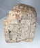 Weathered carved stone religious fragment featuring Christ crucified in medieval devotional style