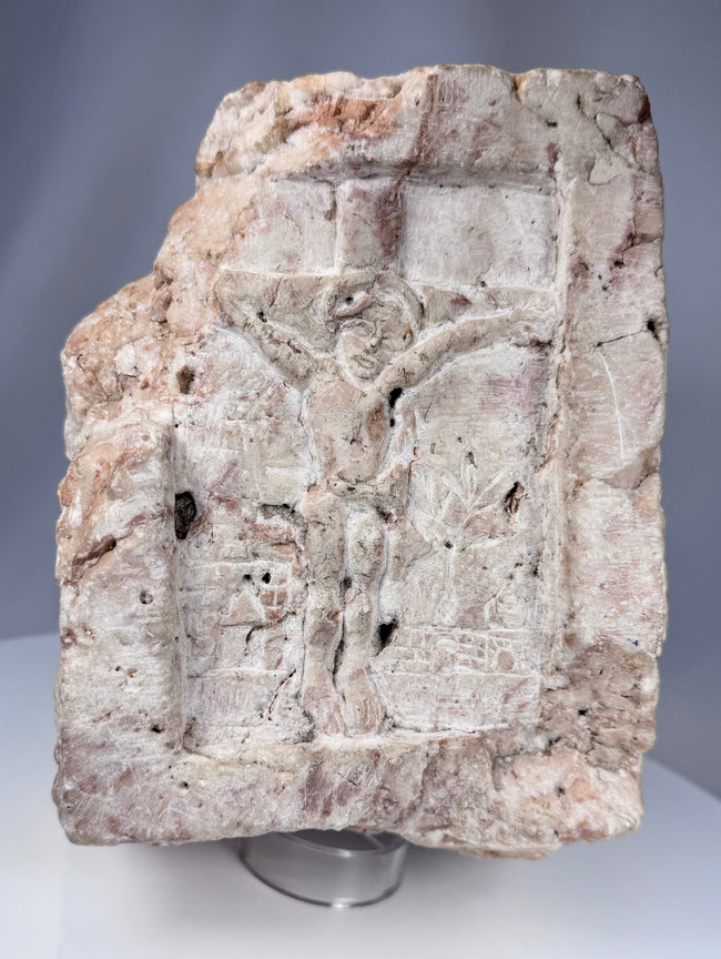 Antique European ecclesiastical stone relief showing a crucifixion scene with carved buildings and tree motif