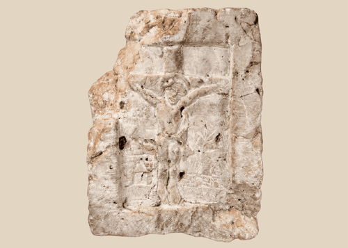 Medieval carved stone fragment depicting Christ on the Cross within an architectural niche with surrounding relief details