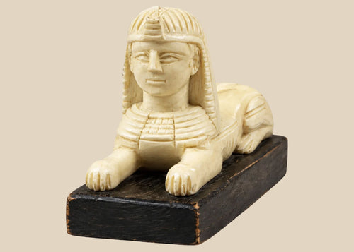 Egypt-inspired carved Sphinx figure with pharaonic nemes headdress on black wooden base, Early–Mid 20th Century.