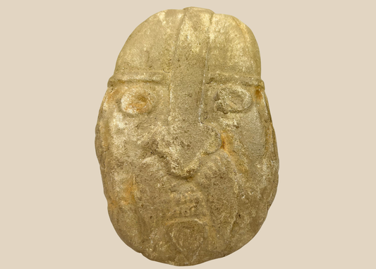 Carved stone warrior effigy head with helmet and bold facial features
