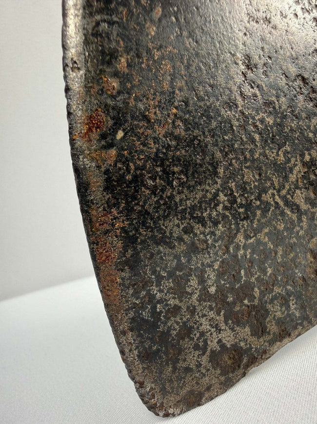 Early cast iron axe head with broad splitting blade, triangular socket, and weathered surface