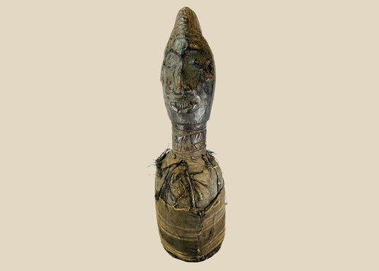 Hand-carved Central or West African wooden figure with elongated facial features, natural fiber torso wrapping, and traces of organic pigments, standing on a white background.