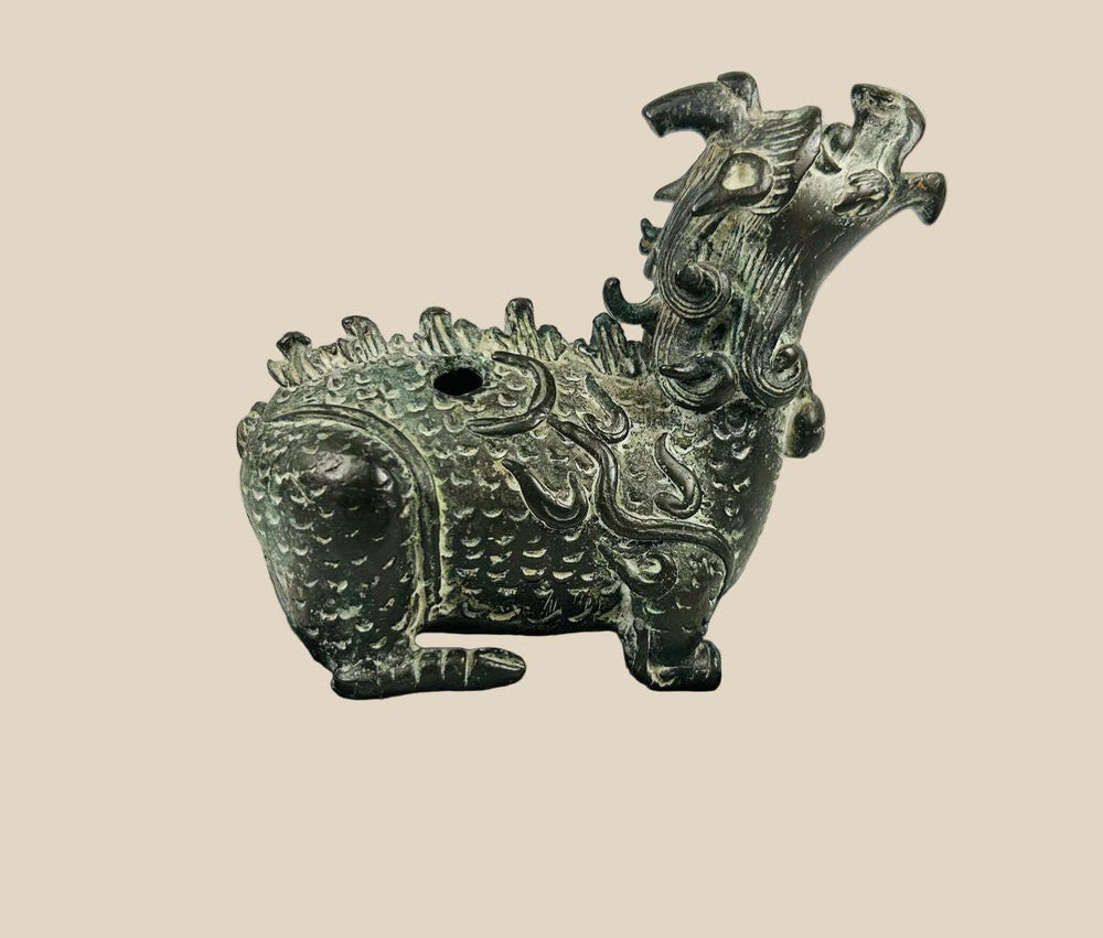 Chinese bronze censer in the form of a mythical Qilin with detailed scales, flame motifs, and open mouth for incense diffusion, mounted on a black display base.