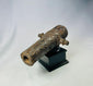 Rusted miniature iron cannon from the British Civil War period, mounted on a black display stand, featuring original trunnions and hollow barrel, 17th century.