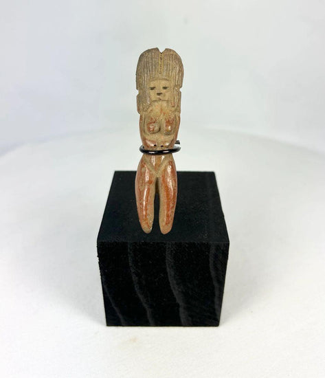 Molded terracotta figurine of seated female from Classic Veracruz culture, with vertical ridged headdress, bent legs, hands raised to face, incised facial features, and traces of red slip; mounted on black display stand; circa 600–900 CE, Gulf Coast of Mexico.