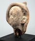 Ancient Mediterranean terracotta sculpture fragment showing a calm expression, aged patina, and partially preserved head covering.