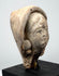 Mediterranean terracotta head from classical antiquity with weathered features, sculpted hair or head covering, and aged earthen surface.