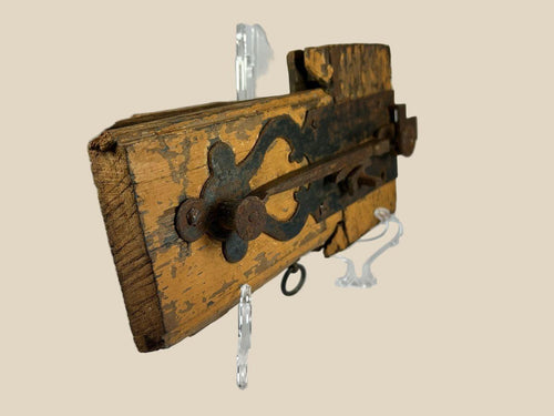 Rare 18th-century colonial wooden locking mechanism with original hand-forged iron hardware, including bolt, latch, and key ring; mounted on aged yellow-painted wood with visible wear, rusted fittings, and patina, illustrating early security technology and craftsmanship of the colonial era.