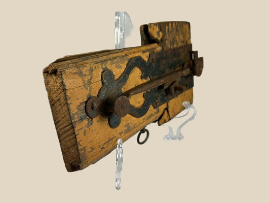 Rare 18th-century colonial wooden locking mechanism with original hand-forged iron hardware, including bolt, latch, and key ring; mounted on aged yellow-painted wood with visible wear, rusted fittings, and patina, illustrating early security technology and craftsmanship of the colonial era.