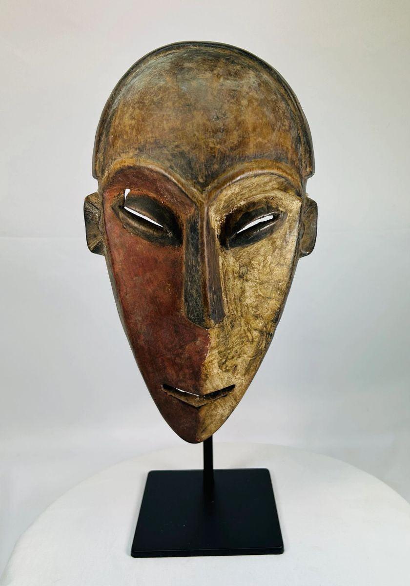Authentic Dan tribal mask from Côte d’Ivoire, carved wood with dual-tone pigments, elongated eyes, and patina from ritual use, circa 1930–1950.