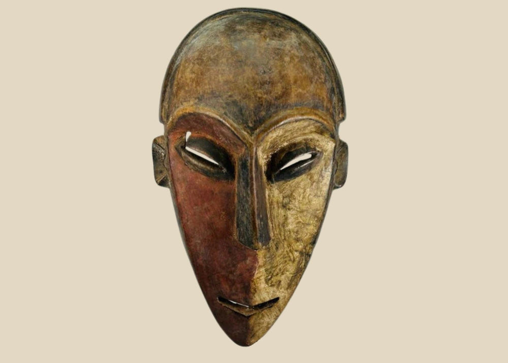 Authentic Dan tribal mask from Côte d’Ivoire, carved wood with dual-tone pigments, elongated eyes, and patina from ritual use, circa 1930–1950.