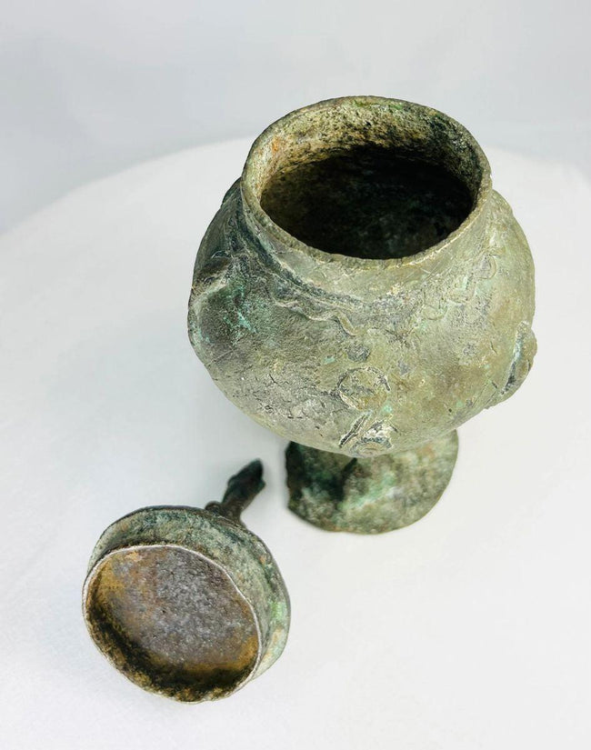 West African Dogon bronze vessel showing sculpted human figure and bulbous ritual form.