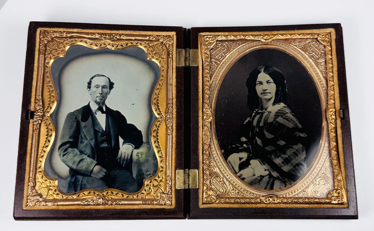 Rotating view of a mid-19th-century double ambrotype set with portraits of a Victorian gentleman and young woman, gilt brass mats, velvet lining, and an ornate molded thermoplastic union case