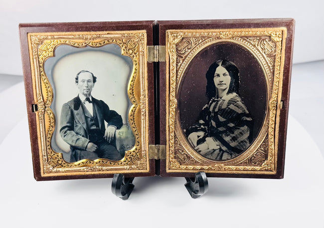 Rotating view of a mid-19th-century double ambrotype set with portraits of a Victorian gentleman and young woman, gilt brass mats, velvet lining, and an ornate molded thermoplastic union case
