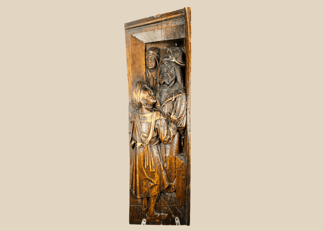 Front-facing view of antique Tudor carved oak panel with two robed figures in high relief.