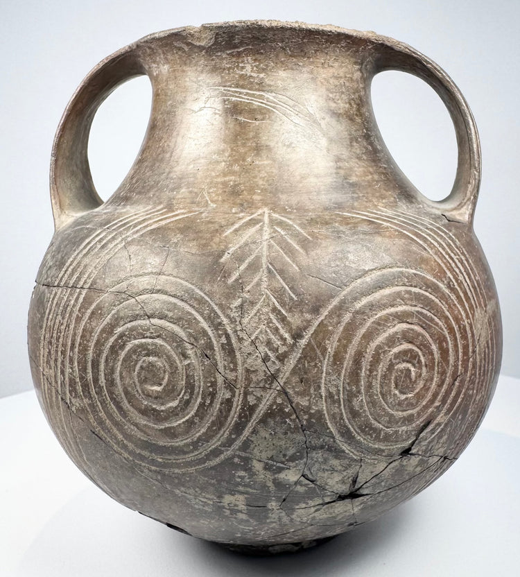 Opposite side of the impasto amphora with one handle prominent and concentric spirals extending across the lower body.