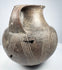 Side of the ancient Etruscan amphora showing one prominent loop handle and spiral ornament continuing around the rounded body.