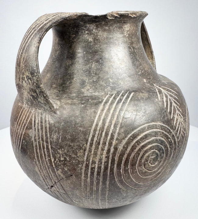 Early Etruscan amphora showing both handles, broad shoulder, and radiating geometric decoration between the large spiral motifs.