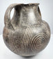 Early Etruscan amphora showing both handles, broad shoulder, and radiating geometric decoration between the large spiral motifs.