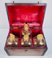 Open Georgian mahogany spirit box displaying four glass decanters, gilt decoration and rich red interior lining