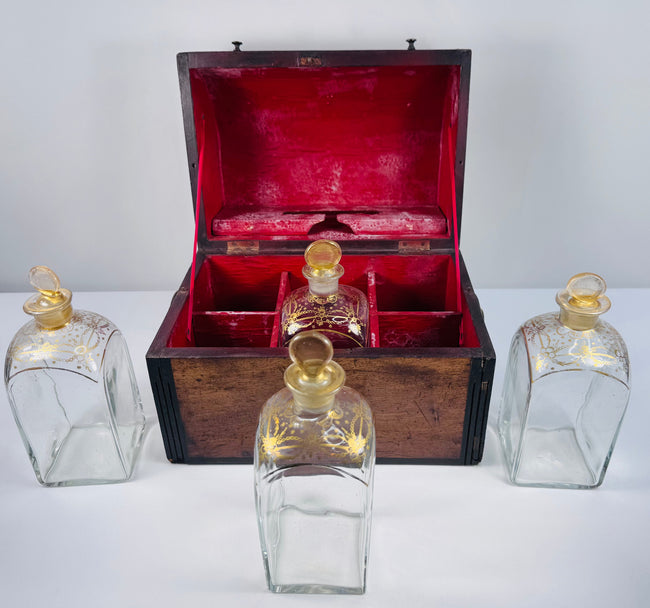 Four antique Georgian square glass spirit decanters with parcel-gilded decoration and matching glass stoppers
