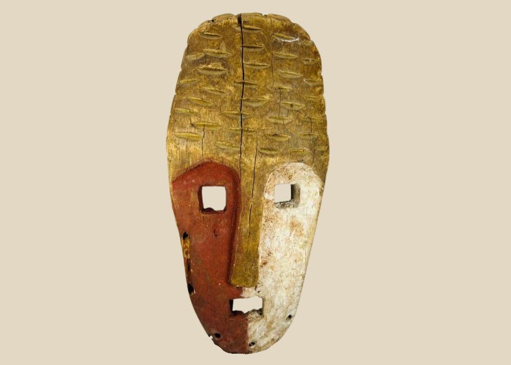Papua New Guinea Sepik River tribal mask, hand-carved hardwood with red ochre and lime pigments, dual-colored face, circa 1900–1940.