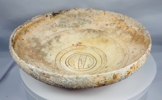 Side profile of a Byzantine slipware bowl showing the red earthenware body and marine encrusted exterior.