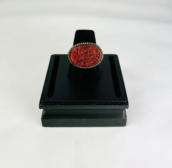Oval carnelian intaglio ring from the Ancient Near East, 1st millennium BCE. Features engraved animal and symbolic motifs on red carnelian, set in a silver bezel, displayed on a black stand. Excellent condition with finely detailed intaglio carvings.