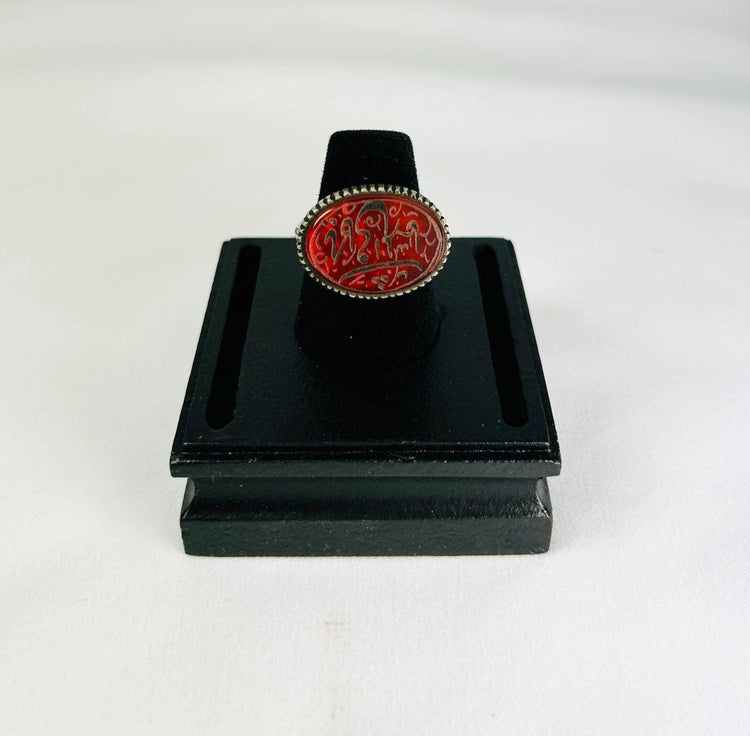 Oval carnelian intaglio ring from the Ancient Near East, 1st millennium BCE. Features engraved animal and symbolic motifs on red carnelian, set in a silver bezel, displayed on a black stand. Excellent condition with finely detailed intaglio carvings.