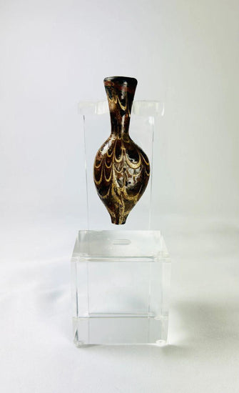 Ancient Eastern Mediterranean core-formed glass alabastron, 5th–6th Century AD, Late Roman to Byzantine period. Teardrop-shaped vessel with slender neck and pointed base, decorated with marbled browns, yellows, and gold, featuring delicate yellow trailing and swirling designs. Used for oils and perfumes, reflecting luxury, artistry, and status in antiquity.