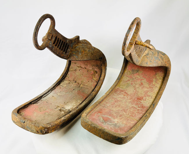 Edo-era Japanese horse stirrups with deep patination, red lacquer interiors, and protective triple-lobed toe guards.