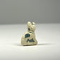 Close detail of an Ancient Egyptian Bastet cat amulet with modeled feline features, mineral deposits, and worn ancient glaze.